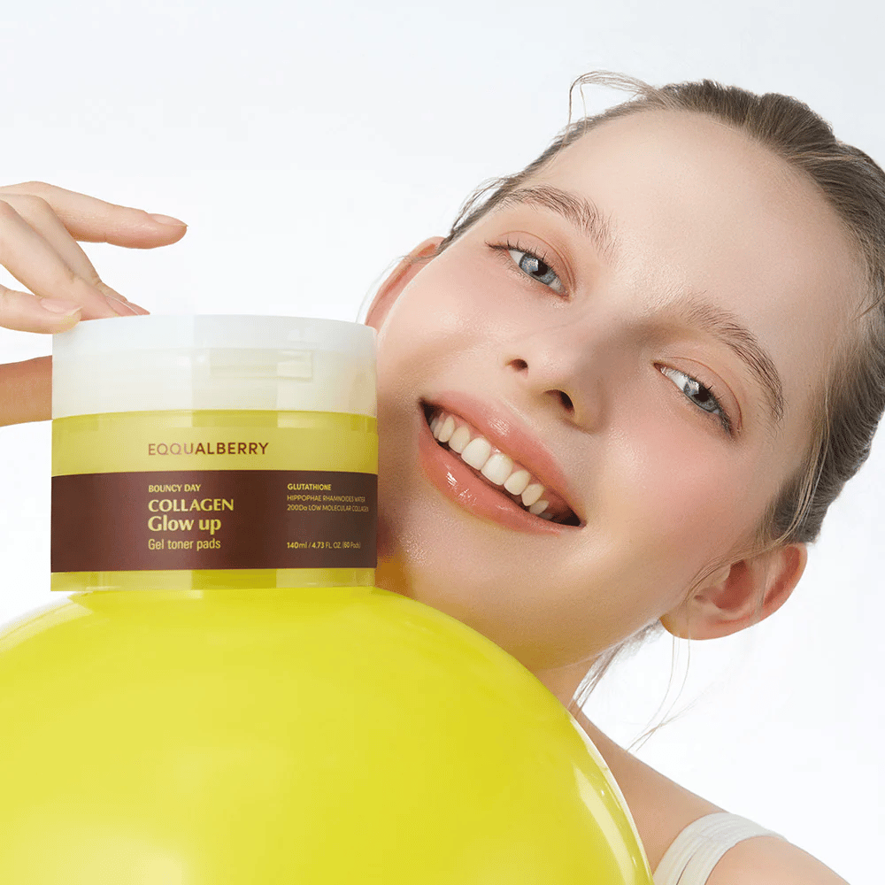 Modelo sorridente segurando Bouncy Day Collagen Glow up Gel Toner Pads, que ajuda a proporcionar um brilho juvenil e firmeza com colágeno de baixa molécula e glutationa.