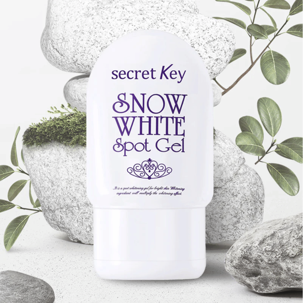 Secret Key Snow White Spot Gel fotografada contra pedras e folhas verdes.