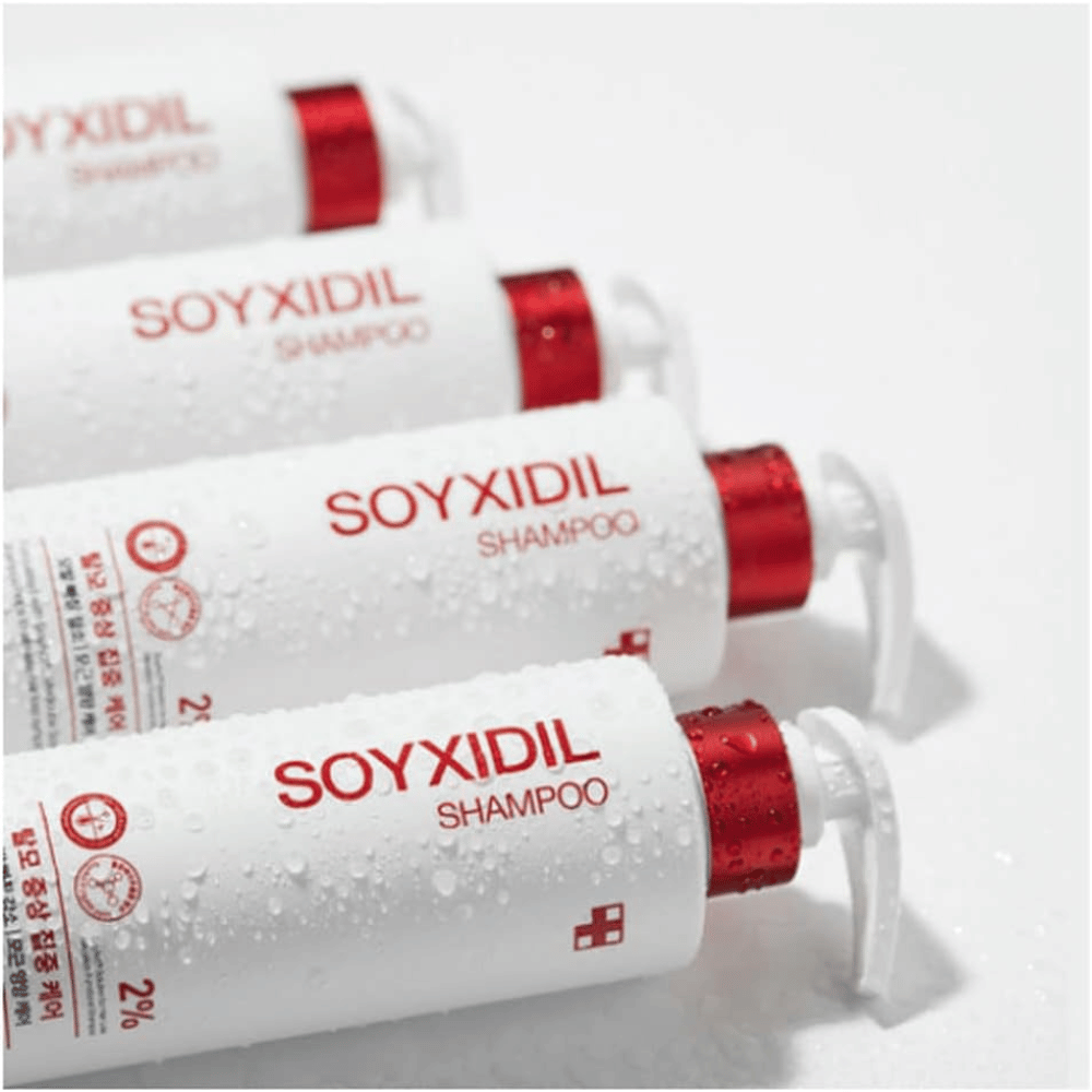 Várias garrafas de Medicube Soyxidil Shampoo alinhadas com gotas de água - mostra a sensação fresca e cuidadosa do produto.