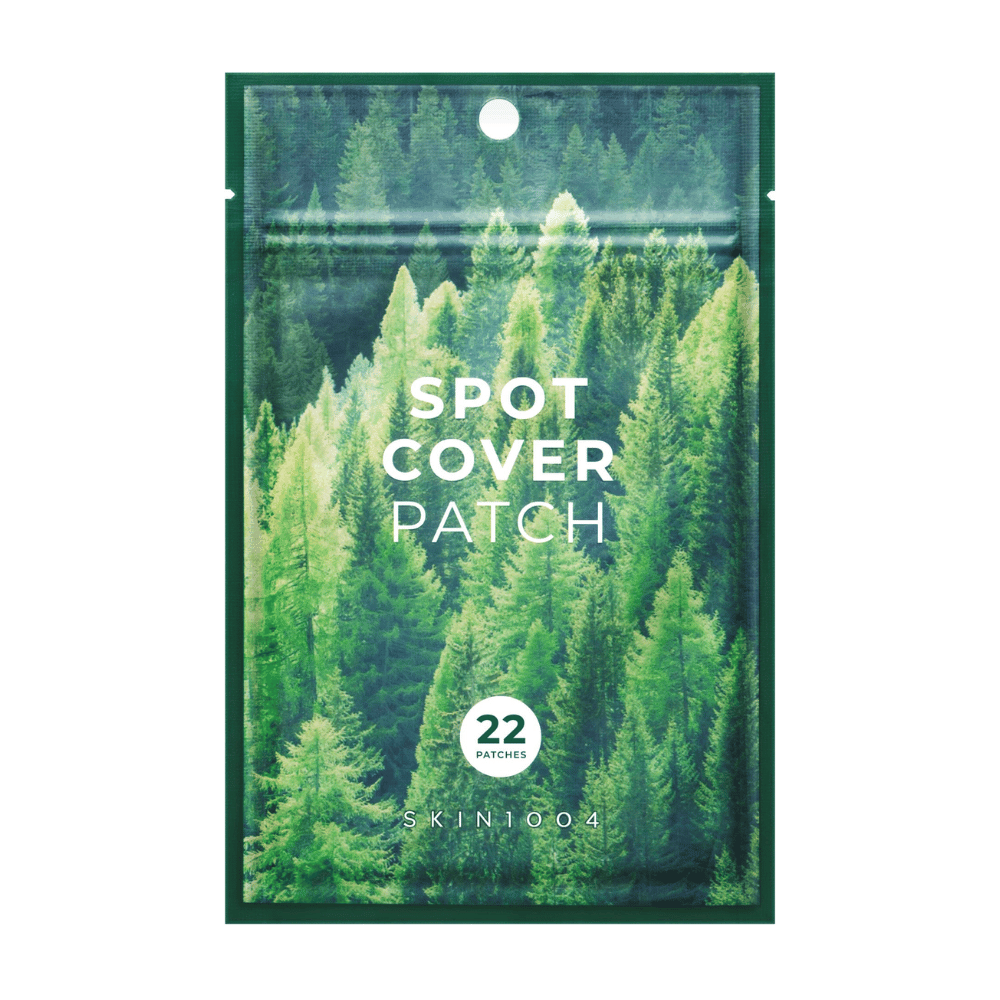 Embalagem com "Spot Cover Patch" que contém 22 adesivos, desenhada com um motivo de floresta verde. O texto "SPOT COVER PATCH" está impresso em branco na frente, e um círculo marca o número de adesivos. O produto é da marca SKIN1004.