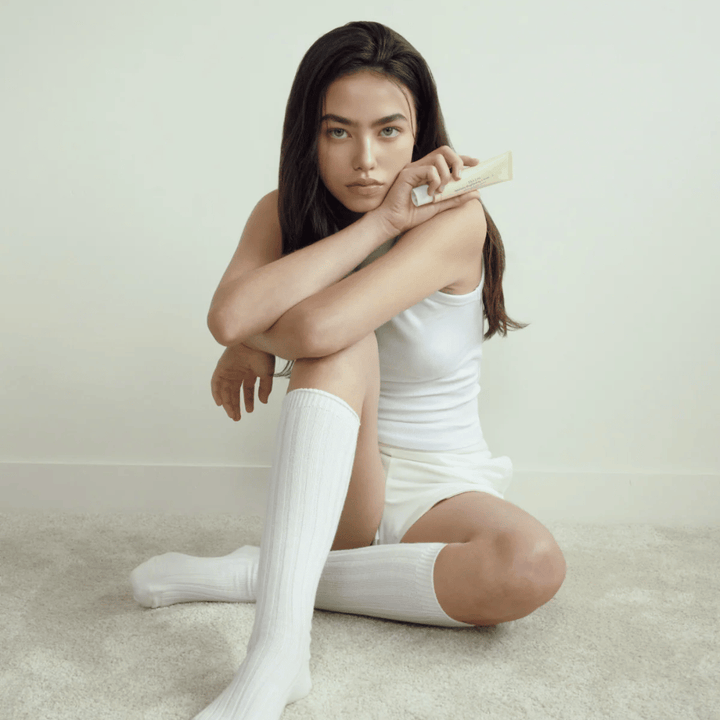 Imagem lifestyle com uma modelo a segurar o produto num ambiente claro e minimalista. A imagem transmite uma sensação de cuidados de pele limpa, natural e calma, associada ao brilho e ao efeito brightening.