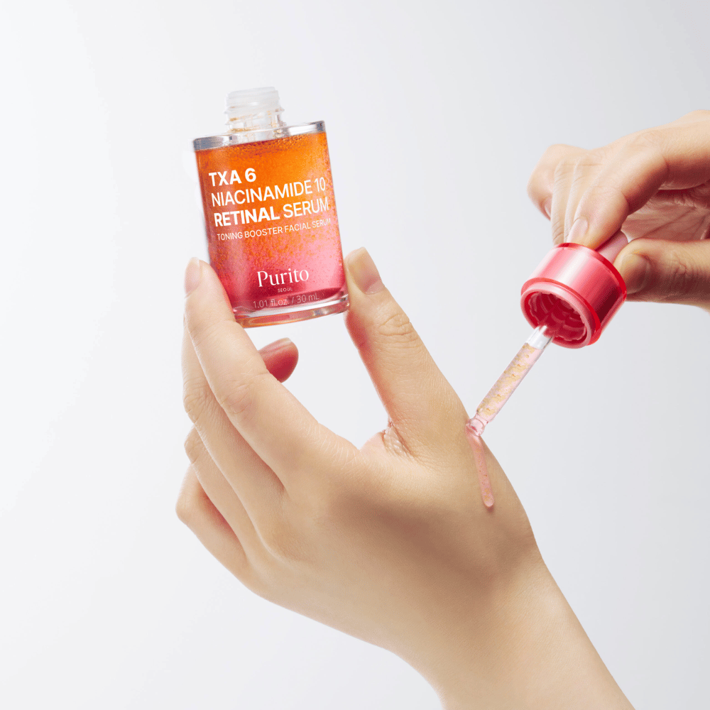 Mão aplicando Purito TXA 6 Niacinamide 10 Retinal Serum. Fórmula leve com ingredientes ativos para luminosidade, elasticidade e pele mais clara.