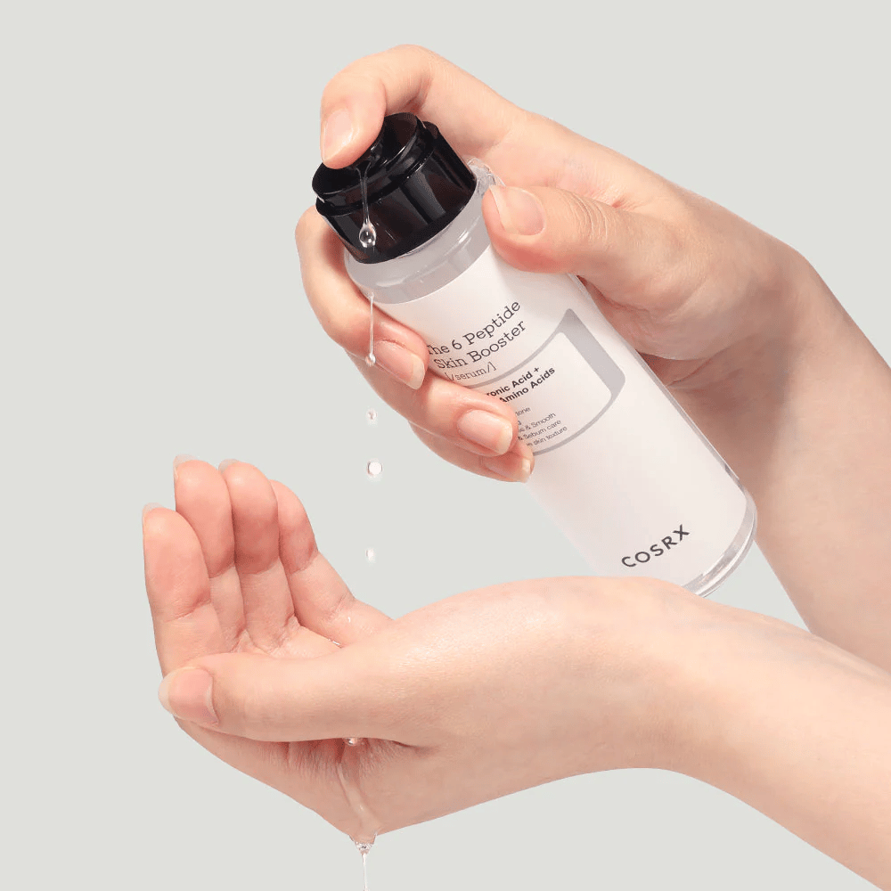 Mãos despejando produto de cuidados da pele de um frasco transparente com o texto "The Peptide Skin Booster".