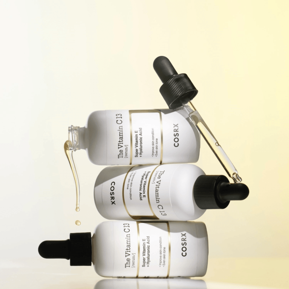 COSRX The Vitamin C 13 Serum com vitamina E e ácido hialurônico, três frascos com pipeta e gotas de sérum de vitamina C para tom de pele desigual e brilho.