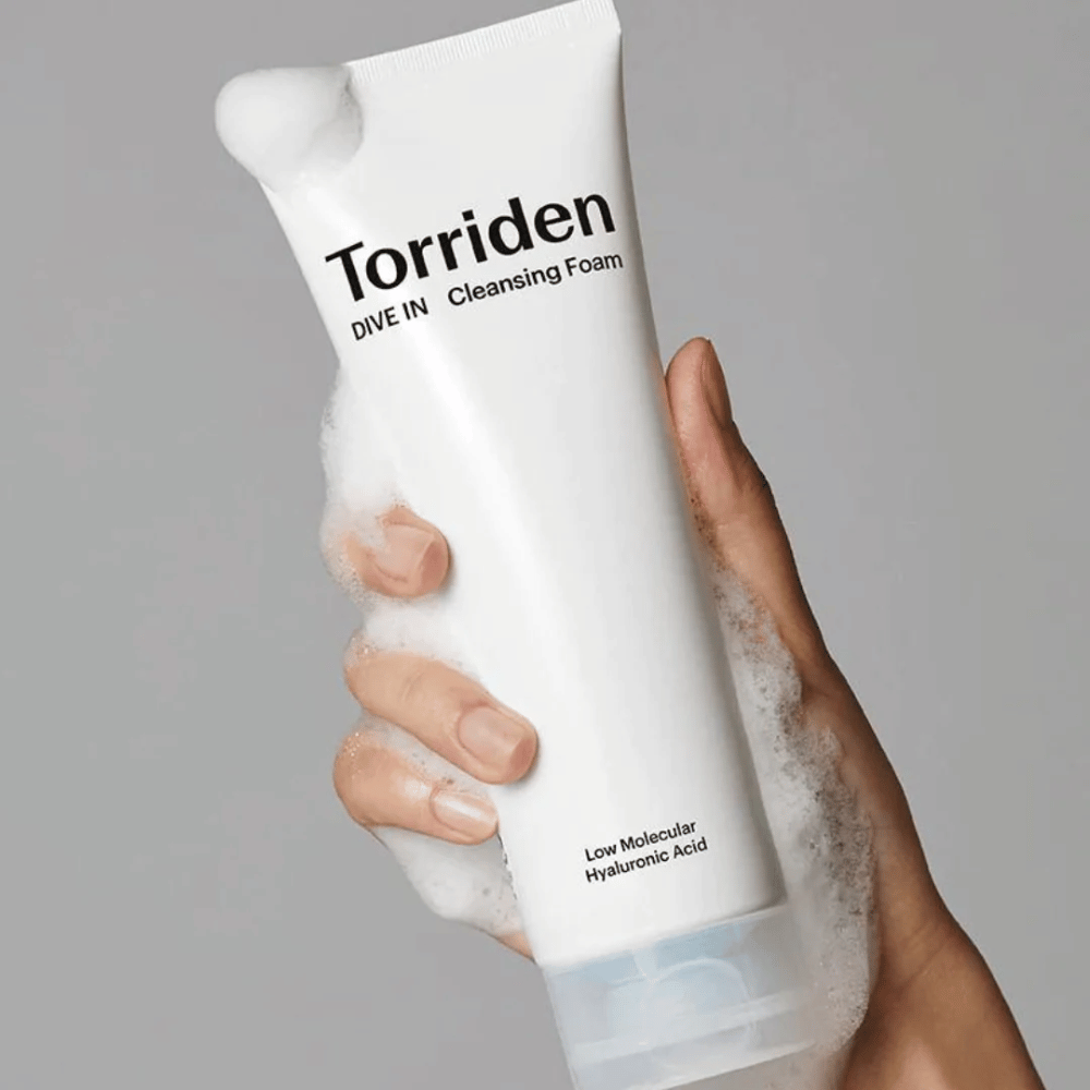 Uma mão segurando um tubo pH-balanceado Torriden DIVE-IN Low Molecular Hyaluronic Acid Cleansing Foam 150ml.