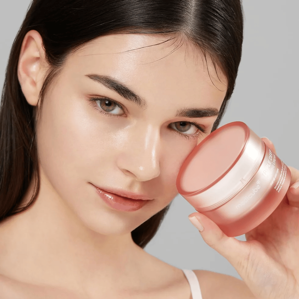 A imagem mostra uma mulher segurando um pote de Triple Collagen Cream. O creme é projetado para melhorar a elasticidade e hidratação da pele. A pele da mulher parece lisa e bem cuidada.




