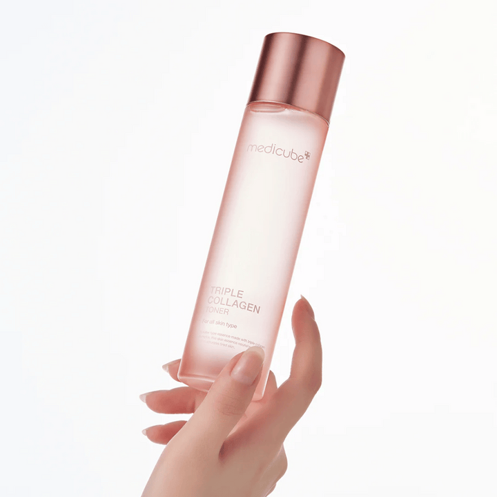Hand som håller i en rosa flaska av Medicube Triple Collagen Toner 4.0, en återfuktande och fasthetsgivande toner för alla hudtyper.