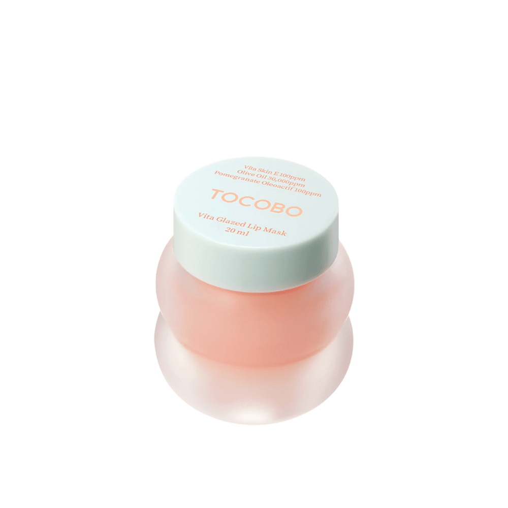 Um frasco com "Vita Glazed Lip Mask" de Tocobo é exibido. O frasco é redondo e transparente com uma tampa turquesa clara. A máscara dentro é levemente rosa e projetada para hidratar e cuidar dos lábios. O produto tem um volume de 20 ml.