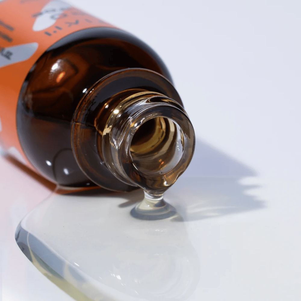 Close-up de TIA'M Vita C Source-sérum escorrendo de um frasco de vidro castanho. A fórmula clara do sérum destaca o seu conteúdo concentrado de vitamina C para uma pele radiante.