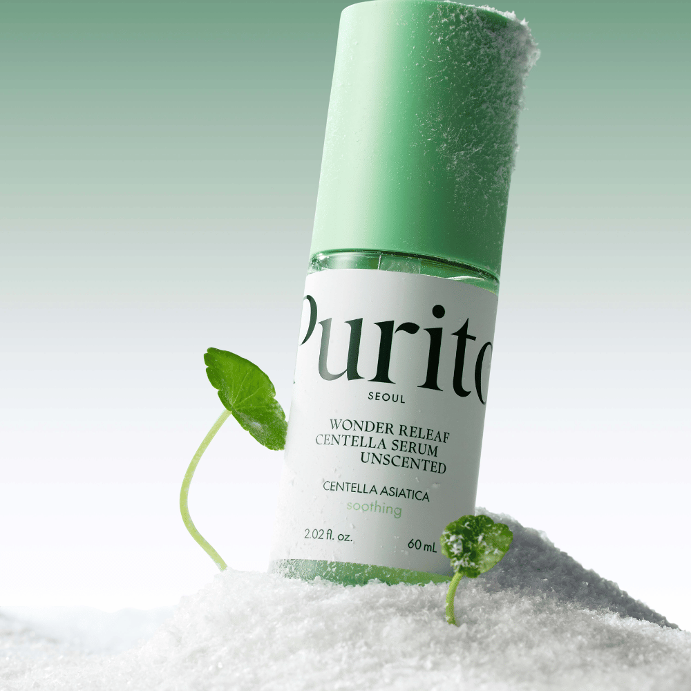 Garrafa com Purito Centella Serum está na neve, folhas verdes são visíveis, contra um fundo verde suave.