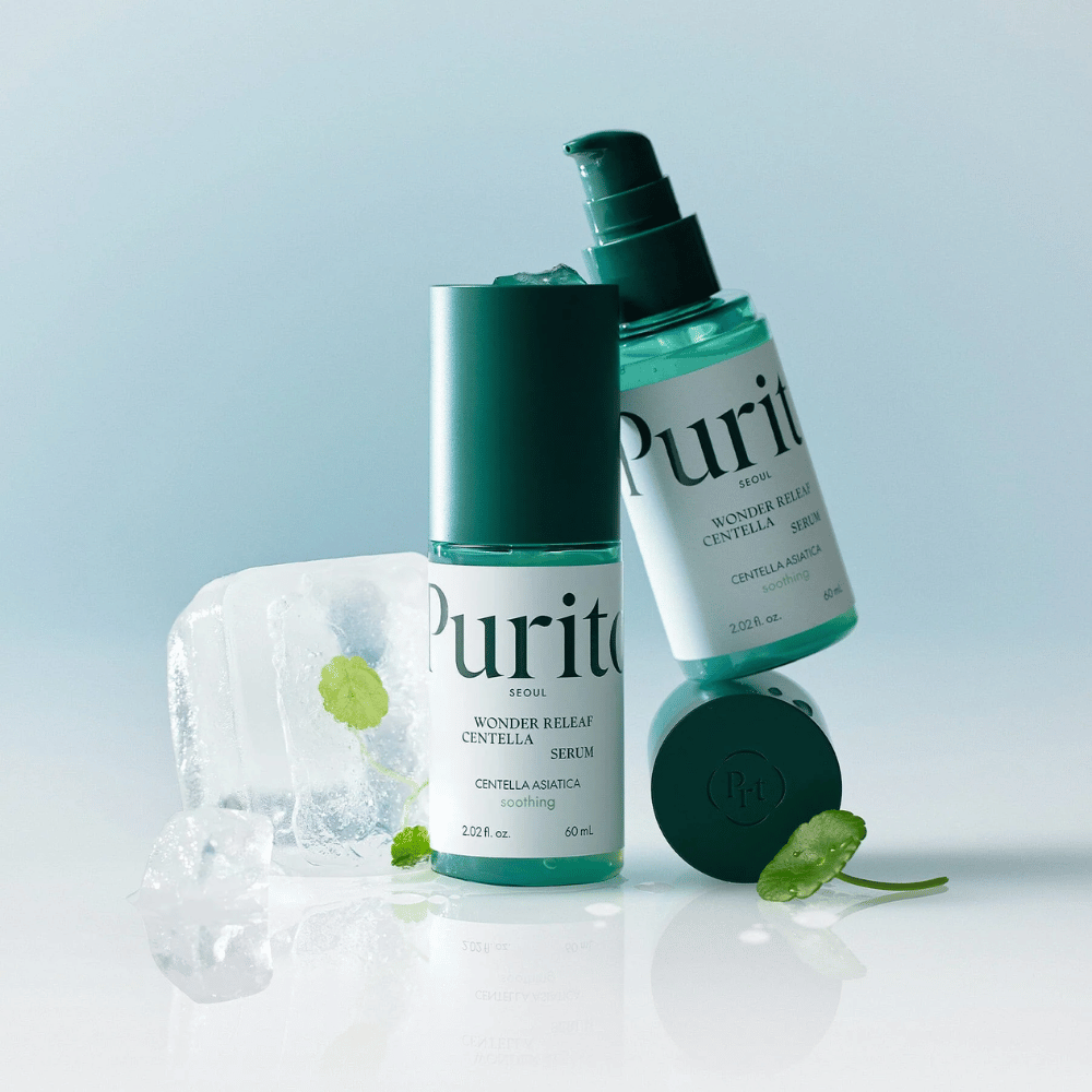 Duas garrafas de Purito Wonder Releaf Centella Serum, uma em pé e outra deitada, cercadas por cubos de gelo com folhas de centella dentro e uma folha solta sobre uma superfície azul clara.