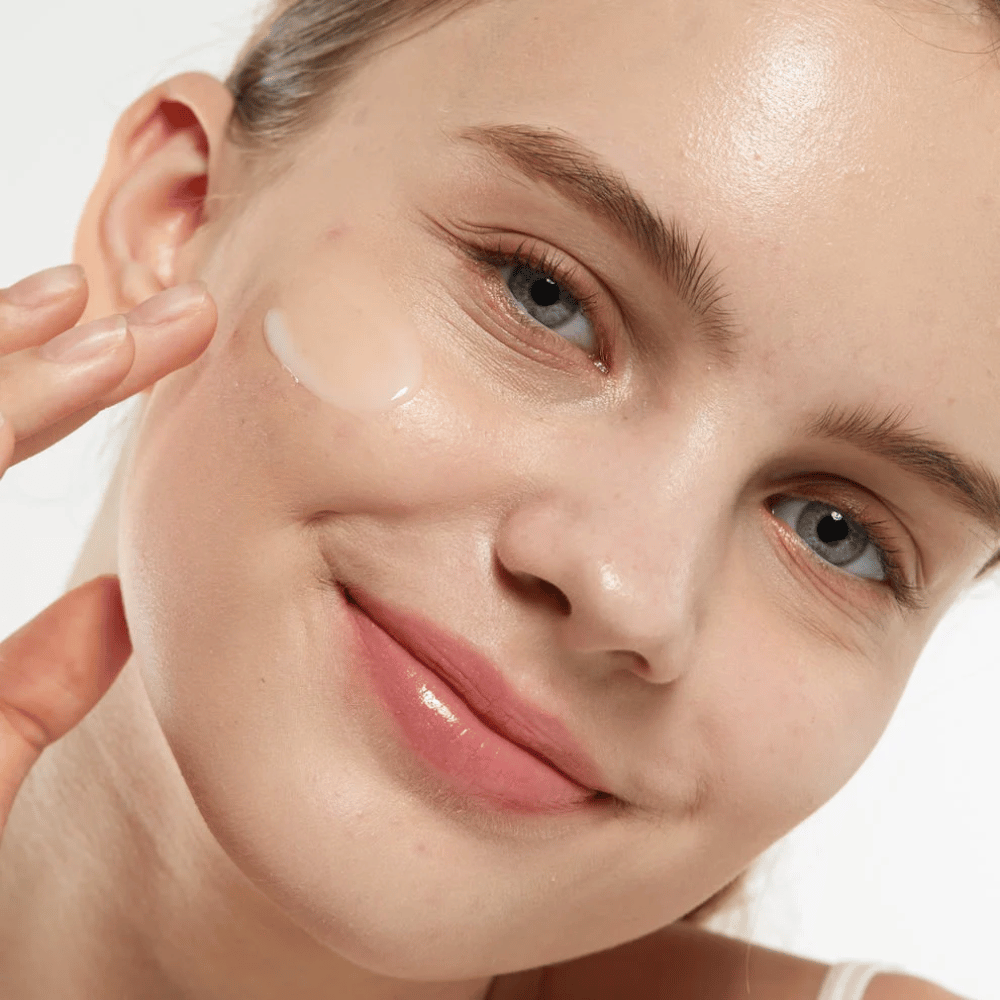 Modelo aplicando Medicube Zero Pore Serum 2.0 na bochecha, um sérum refinador de poros que proporciona uma textura de pele mais uniforme, hidratação e um brilho natural.