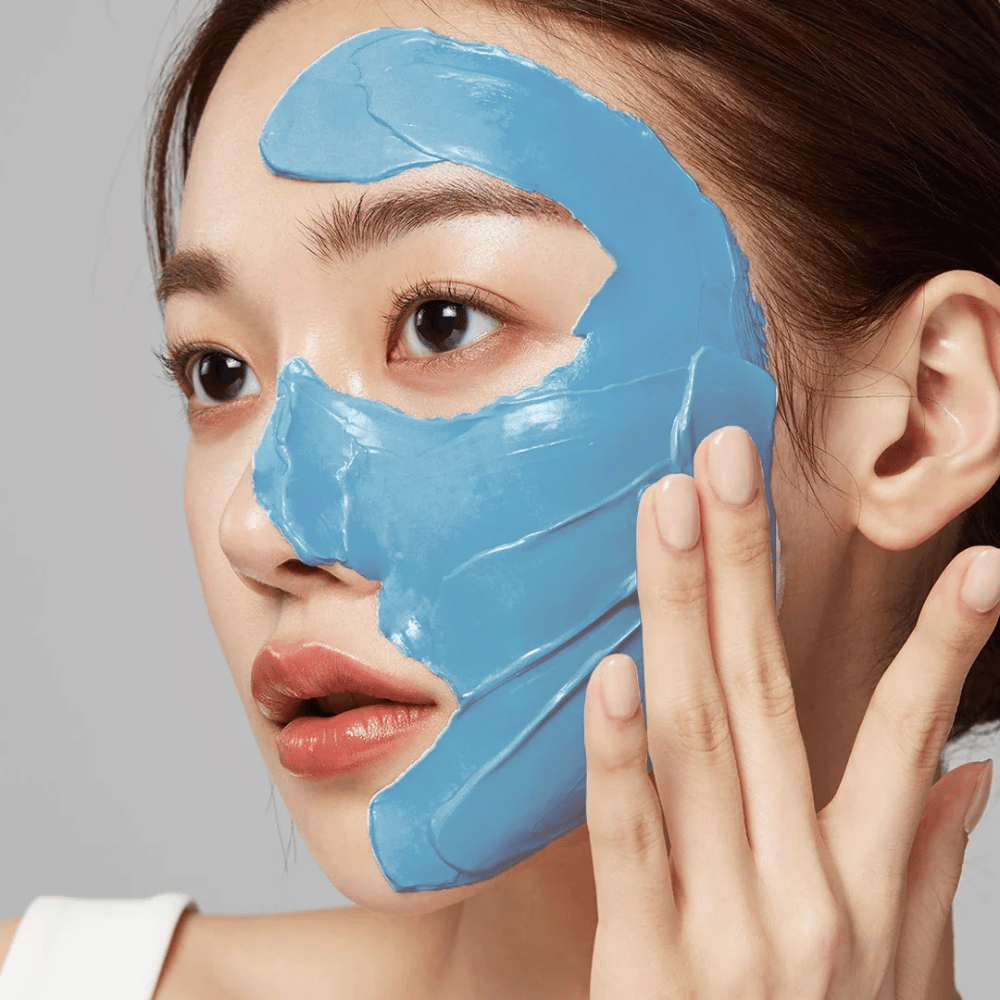 Modelo com máscara facial azul de Medicube, cobrindo a zona T para cuidado dos poros.