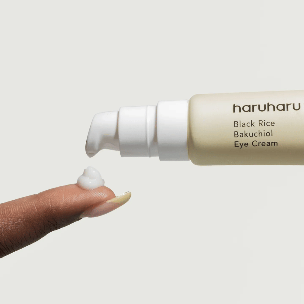 HaruHaru Wonder Black Rice Bakuchiol Eye Cream – close-up da bomba dispensando creme na ponta do dedo, mostrando a consistência para hidratação e anti-envelhecimento.