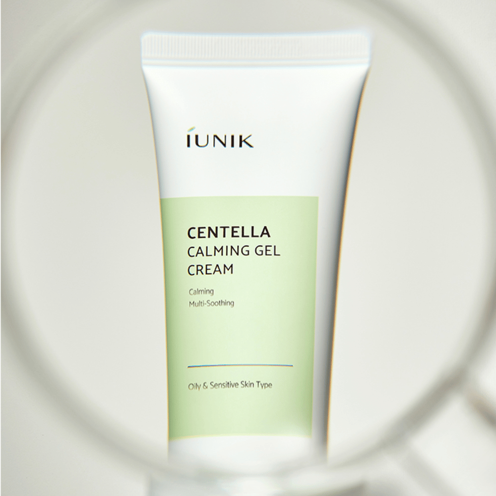 Um tubo iUNIK Centella Calming Gel Cream com design em branco e verde claro está em pé, visto através de uma moldura redonda semelhante a uma lupa.