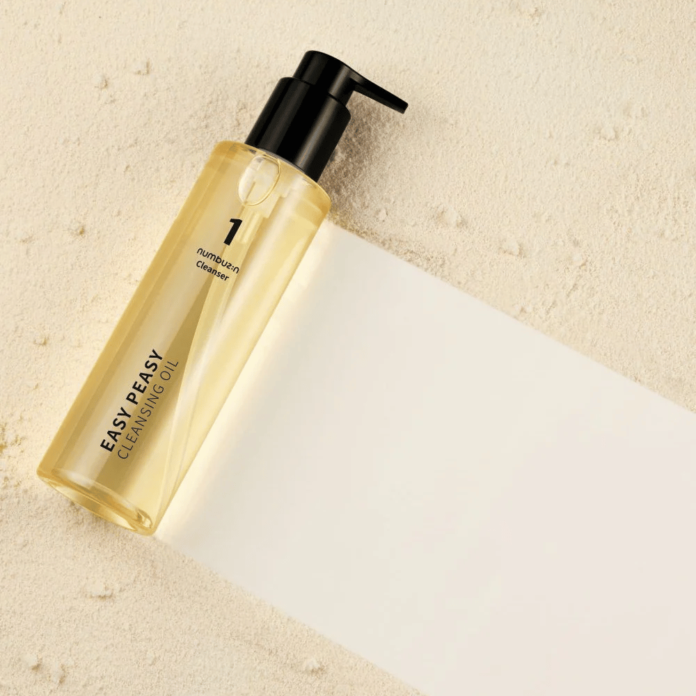 Numbuzin No.1 Easy Peasy Cleansing Oil deitado sobre superfície cor de areia com sombra.