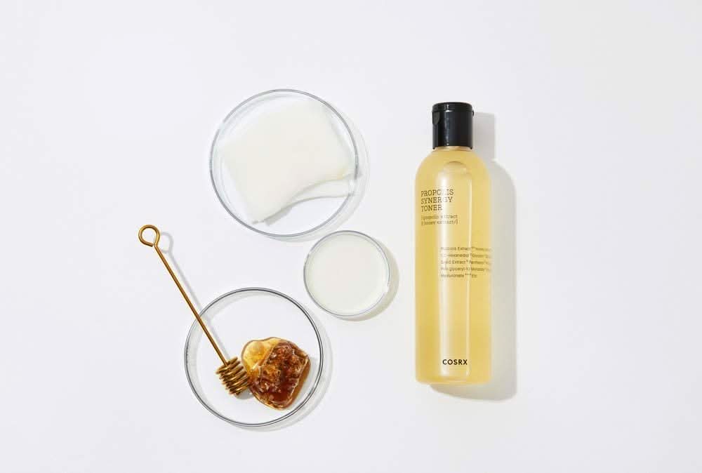 Uma garrafa COSRX Full Fit Propolis Synergy Toner 150ml com efeitos anti-inflamatórios e antibacterianos, colocada sobre uma superfície branca.