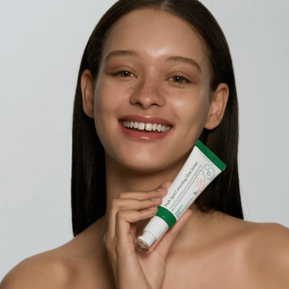 Uma jovem segura um tubo de AXIS - Y Dark Spot Correcting Glow Serum 50ml.