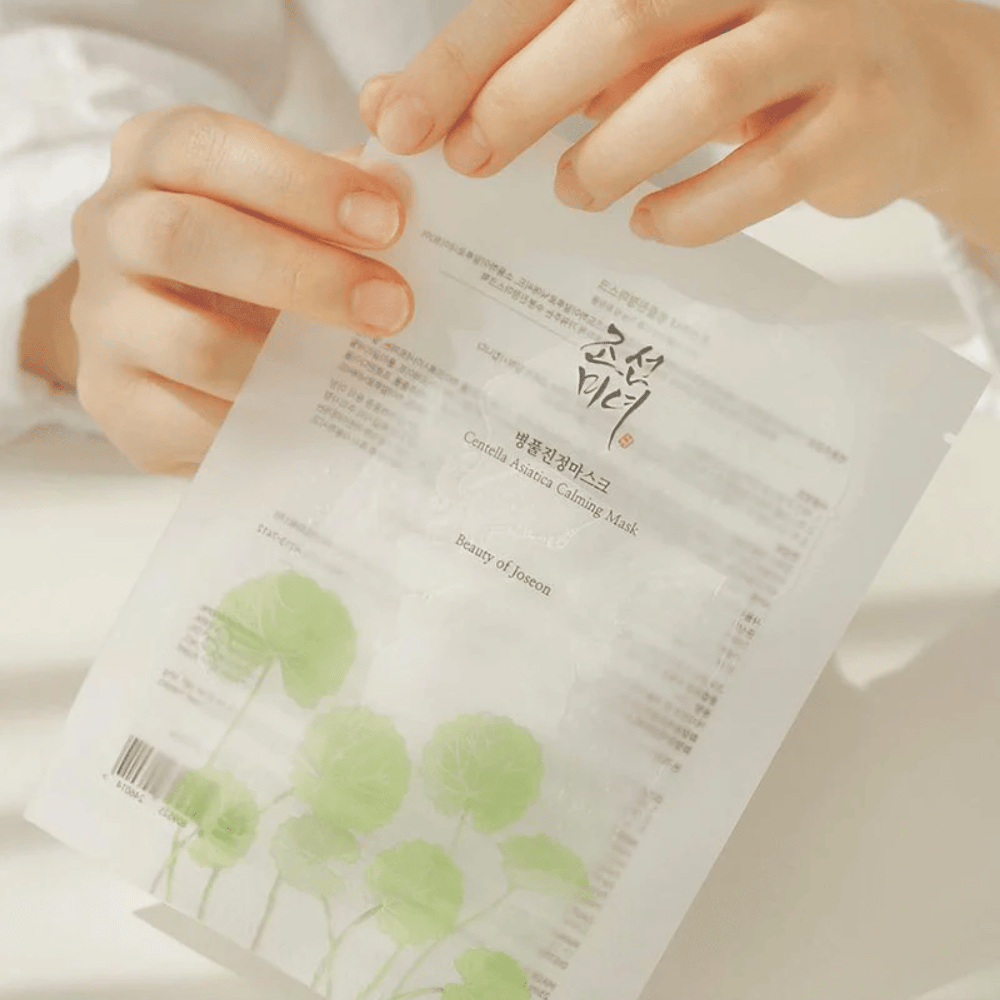 Uma pessoa segurando uma folha de papel com um Beauty of Joseon Centella Asiatica Calming Mask 1 unid.