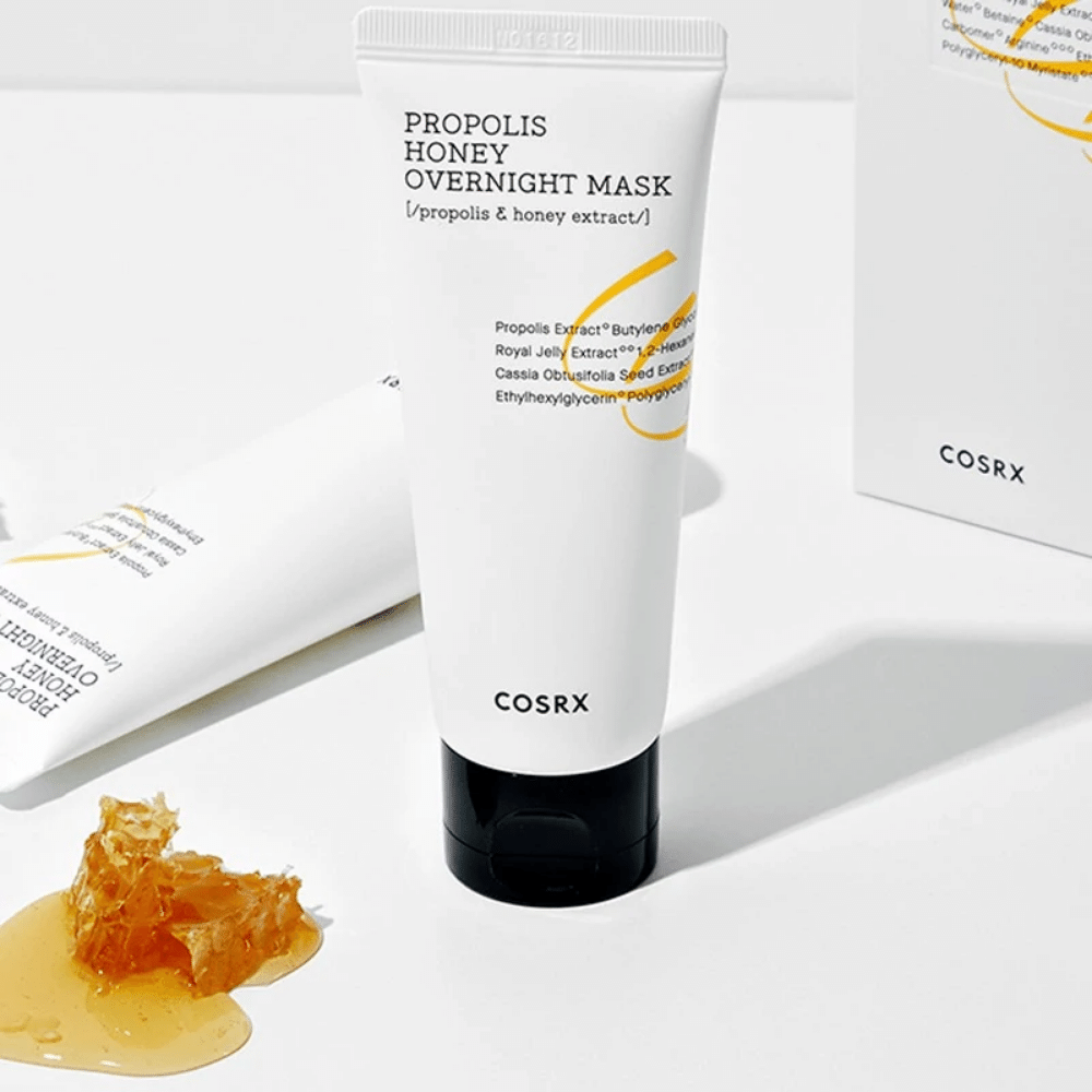 Uma caixa Full Fit Propolis Honey Overnight Mask 60ml de COSRX com uma garrafa de mel ao lado, com extrato de própolis.