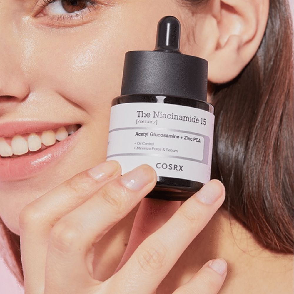 Uma mulher segura uma garrafa de COSRX Niacinamida 15 Serum 20ml para niacinamida e produção de sebo.
