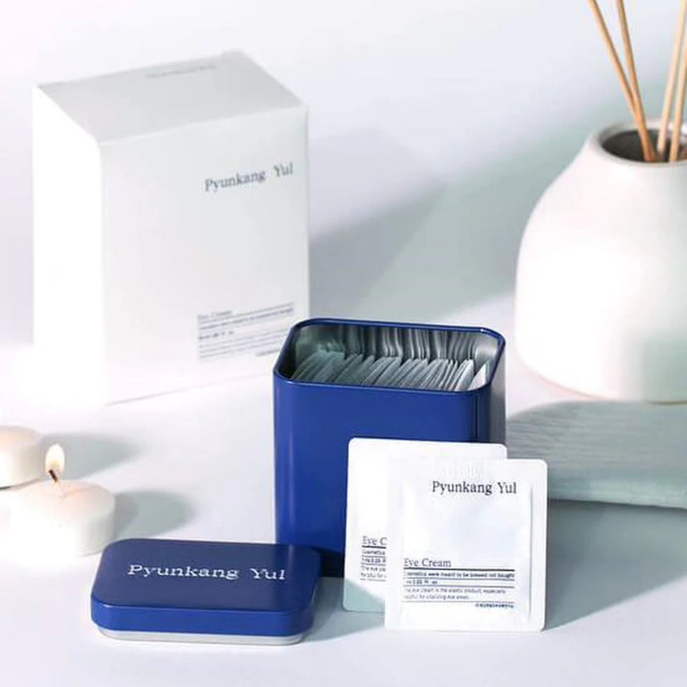 Uma caixa branca com tampa azul e Pyunkang Yul Creme para os Olhos 1ml x 50 unidades ao lado.
