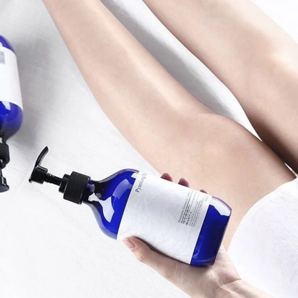 Uma mulher segurando uma garrafa Pyunkang Yul Intensive Ceramide Lotion 500ml ao lado de suas pernas.