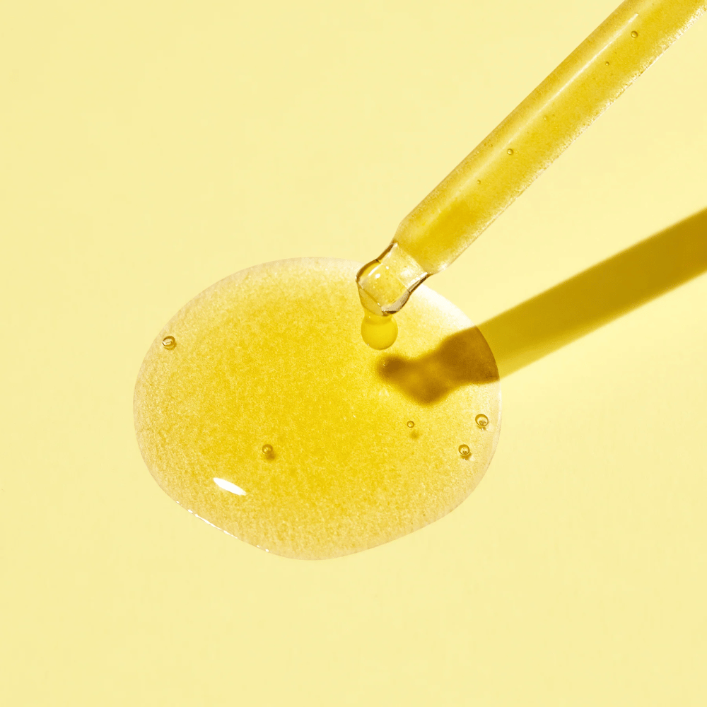 Uma gota de líquido em um fundo amarelo, com MISSHAs Vita C Plus Spot Correcting & Firming Ampoule.