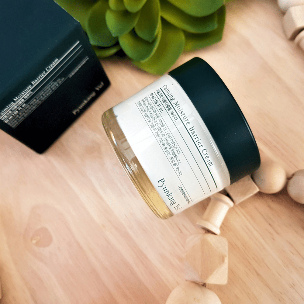 Um frasco Pyunkang Yul Calming Moisture Barrier Cream 50ml que está em cima de uma mesa de madeira.