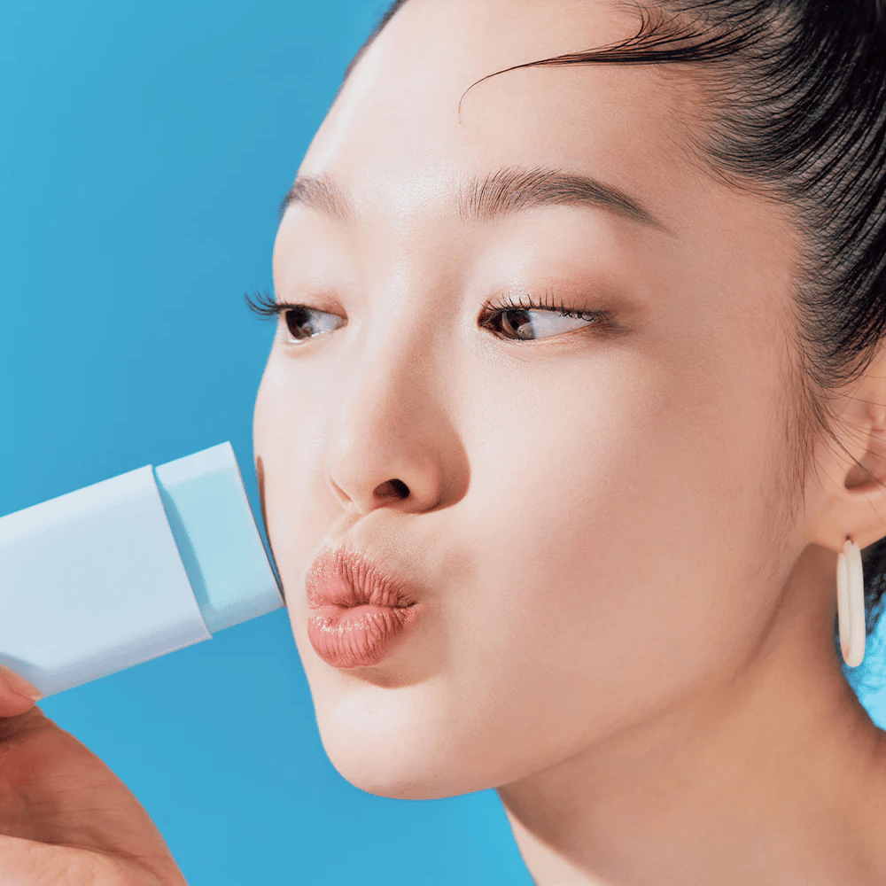 Uma mulher usa um TOCOBO Cotton Soft Sun Stick SPF50+ PA++++ 19g para limpar o rosto.