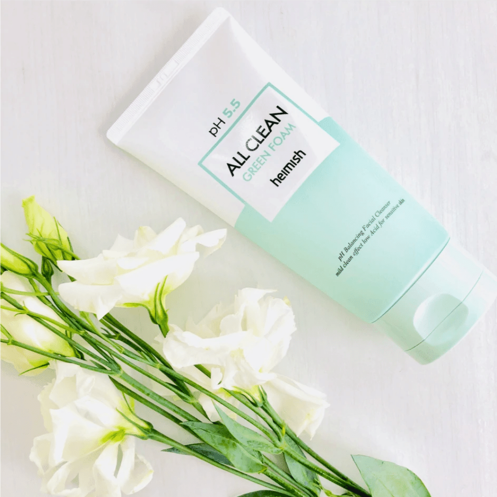 Um tubo heimish All Clean Green Foam 150ml ao lado de flores brancas.